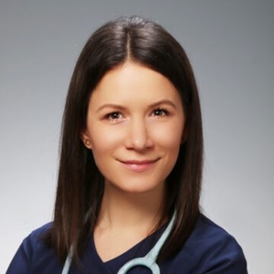 Kobieta o prostych ciemnych włosach w granatowym stroju medycznym ze stetoskopem.