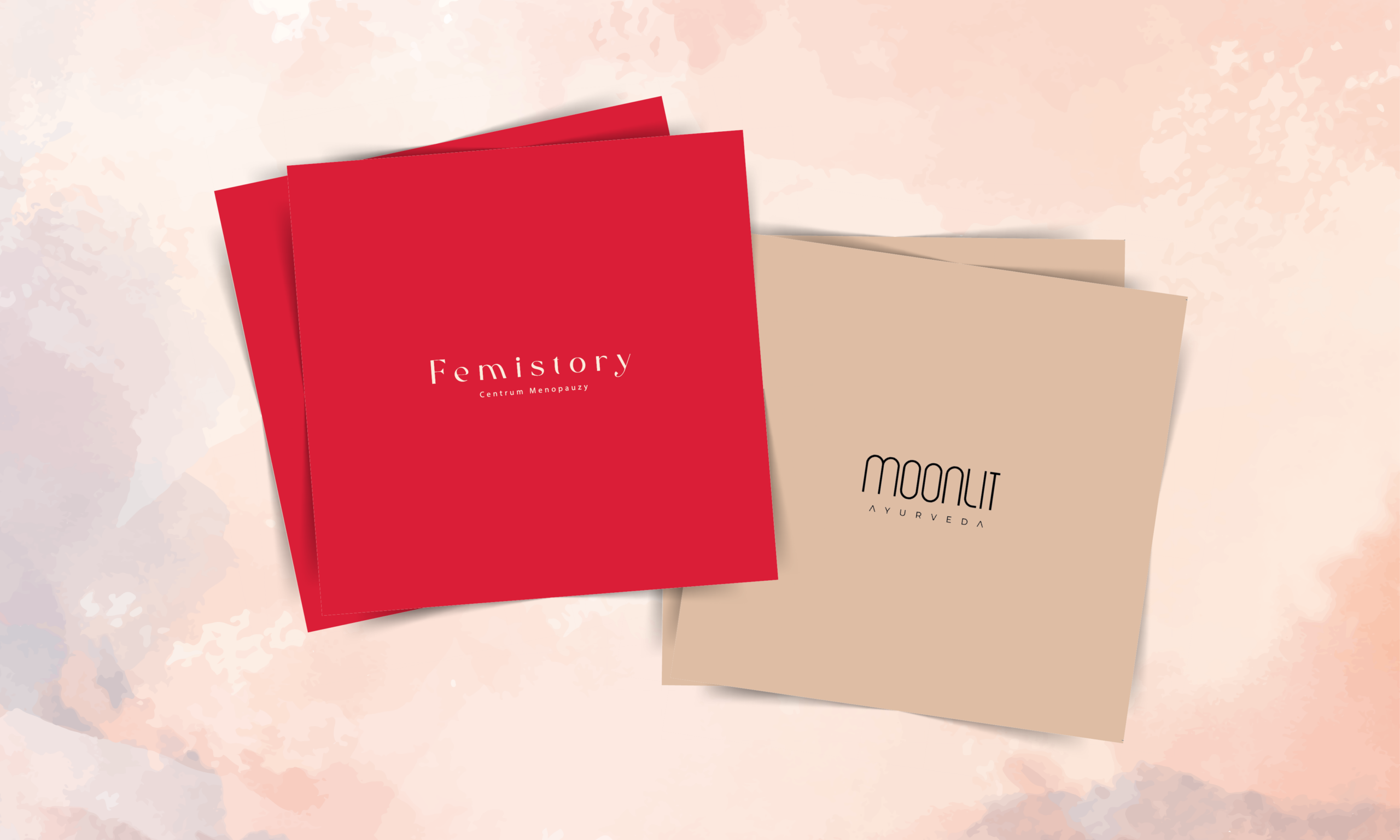 Kompozycja: Centralnie na grafice widoczne są dwie kwadratowe karty podarunkowe, ułożone lekko na siebie pod kątem, na tle z delikatnym, akwarelowym wzorem w odcieniach beżu, różu i pomarańczu. Karta po lewej (czerwona): Jest w intensywnym, jednolitym kolorze czerwonym. Na środku widnieje biały tekst: Femistory (dużą czcionką) oraz poniżej mniejszymi literami Centrum Menopauzy. Karta po prawej (beżowa): Jest w jasnym, neutralnym kolorze beżowym (piaskowym). Na dole, czarną czcionką, umieszczone jest logo i nazwa: MOONLIT (stylizowana, łukowata czcionka) oraz poniżej mniejszymi literami AYURVEDA.